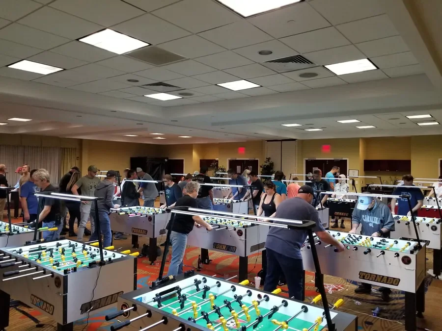 A tournament hall with rows of Tornado tables and players mid-match