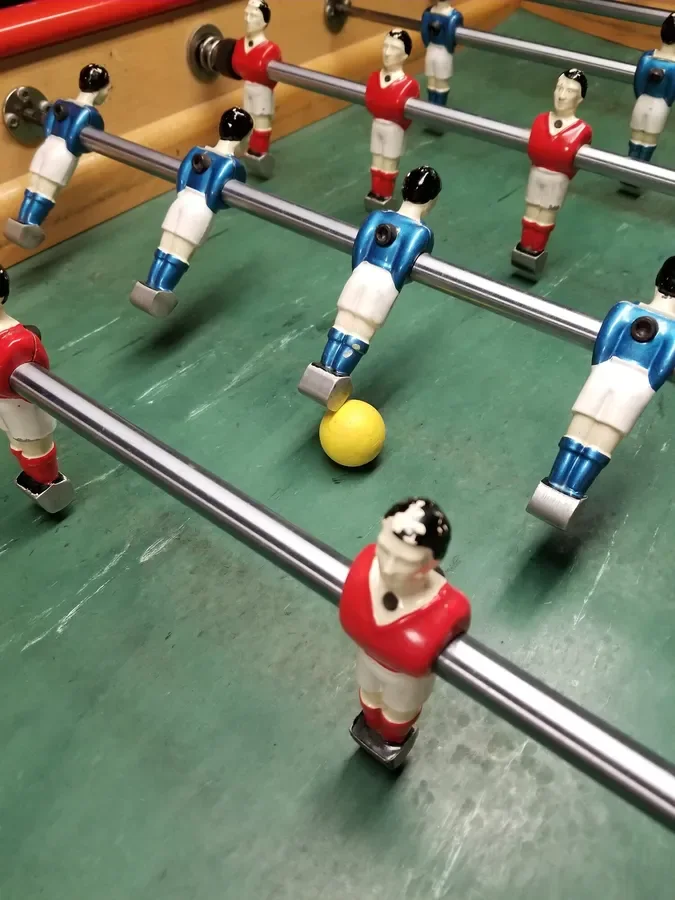 Close-up of foosmen and a yellow ball on a worn green playfield